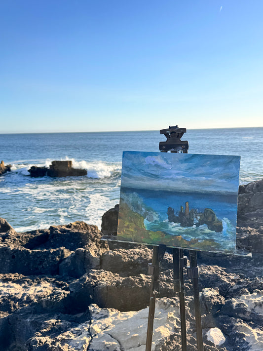 Painting of a coastal scene on an easel by the ocean