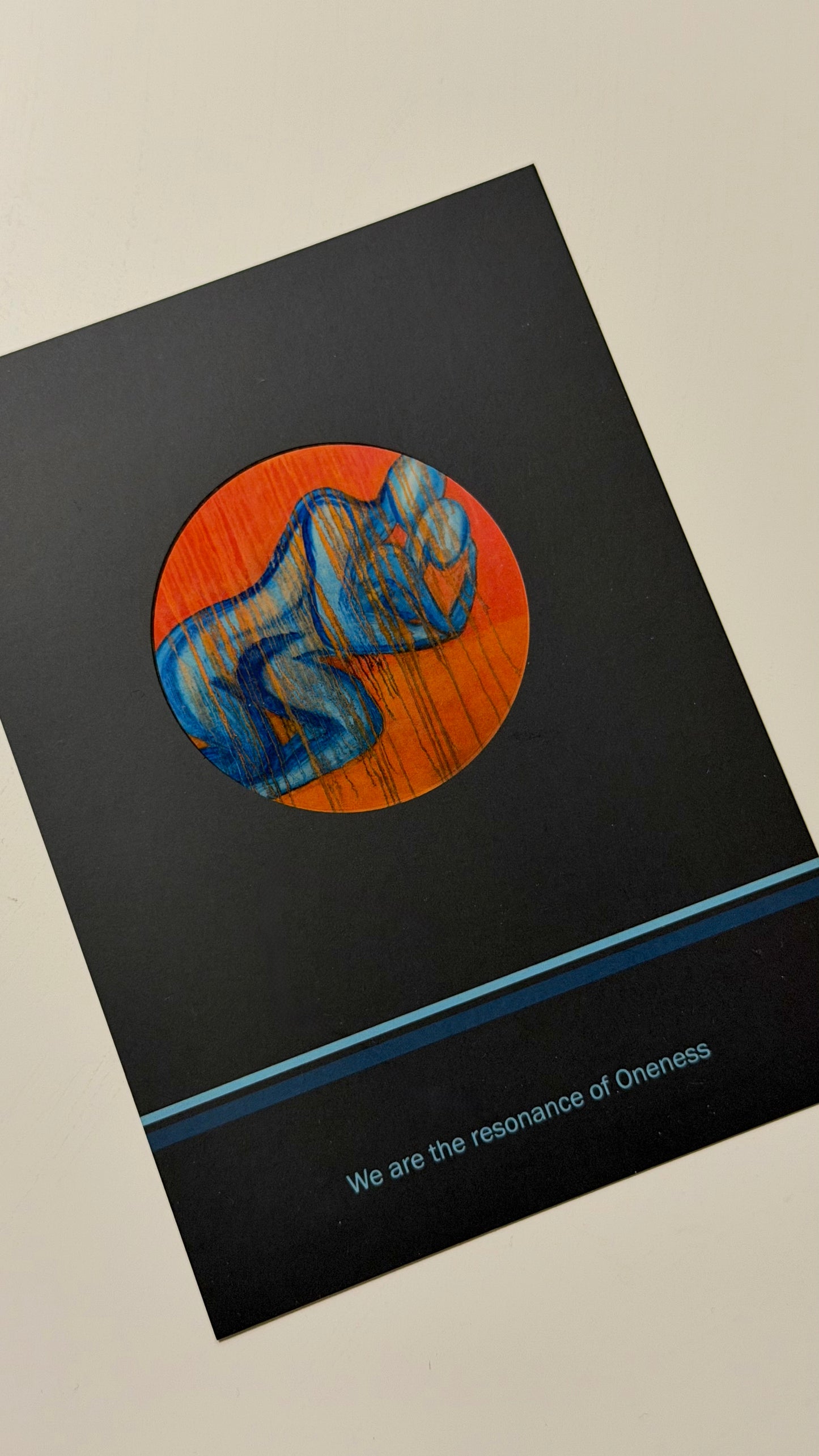 unusual postcard with a circular design featuring a blue couple figure on an orange background, on a black surface.